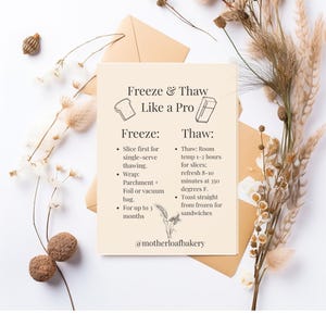 May include: A beige card with the text "Freeze & Thaw Like a Pro" and instructions for freezing and thawing food. The card is on a white surface with dried flowers and two brown envelopes. The card includes the text "@motherloafbakery".