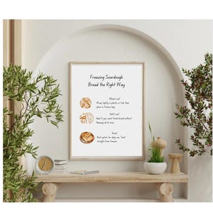 May include: A framed print with the text "Freezing Sourdough Bread the Right Way" and illustrations of bread. The print offers tips for freezing sourdough bread: whole loaf, half loaf, and sliced.