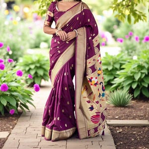 Puede incluir: Un sari de color ciruela con adornos y detalles dorados. El sari presenta un borde decorativo con motivos florales y de pájaros. La tela se drapea con elegancia, mostrando el intrincado diseño y la artesanía. El sari se usa con una blusa a juego.