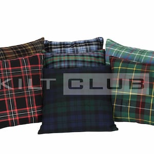 Op de afbeelding: Een verzameling geruite kussens in verschillende kleuren, waaronder zwart, rood, groen, blauw en bruin. De kussens hebben een klassiek tartanpatroon, met de tekst "KILT CLUB" op een van de kussens.
