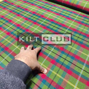 Puede incluir: Tela a cuadros verde, roja y azul con el texto "KILT CLUB". La tela tiene un patrón de tartán con líneas que se cruzan. La tela es una mezcla de colores, incluyendo verde, rojo, azul y amarillo.