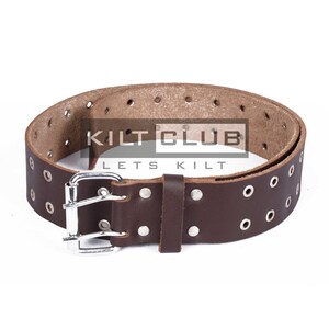May include: Brown leather belt with multiple eyelets and a silver-colored buckle. The belt has a rectangular leather loop and is branded with the text "KILT CLUB LETS KILT".