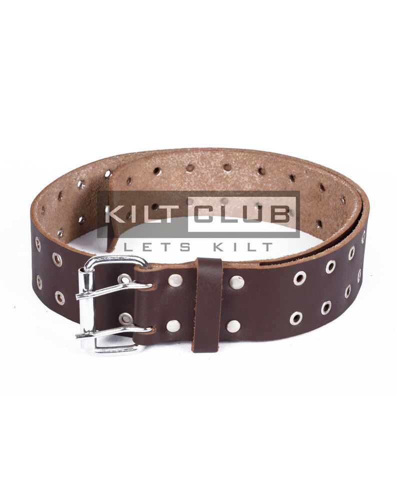 May include: Brown leather belt with multiple eyelets and a silver-colored buckle. The belt has a rectangular leather loop and is branded with the text "KILT CLUB LETS KILT".