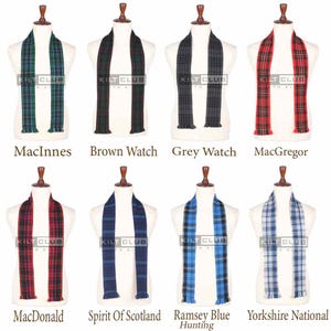 May include: Eight tartan scarves in a variety of colours, including green, red, blue, and grey, displayed on mannequins. Each scarf is labelled with a different name, such as "MacInnes" and "MacGregor". The "Kilt Club" logo is visible.