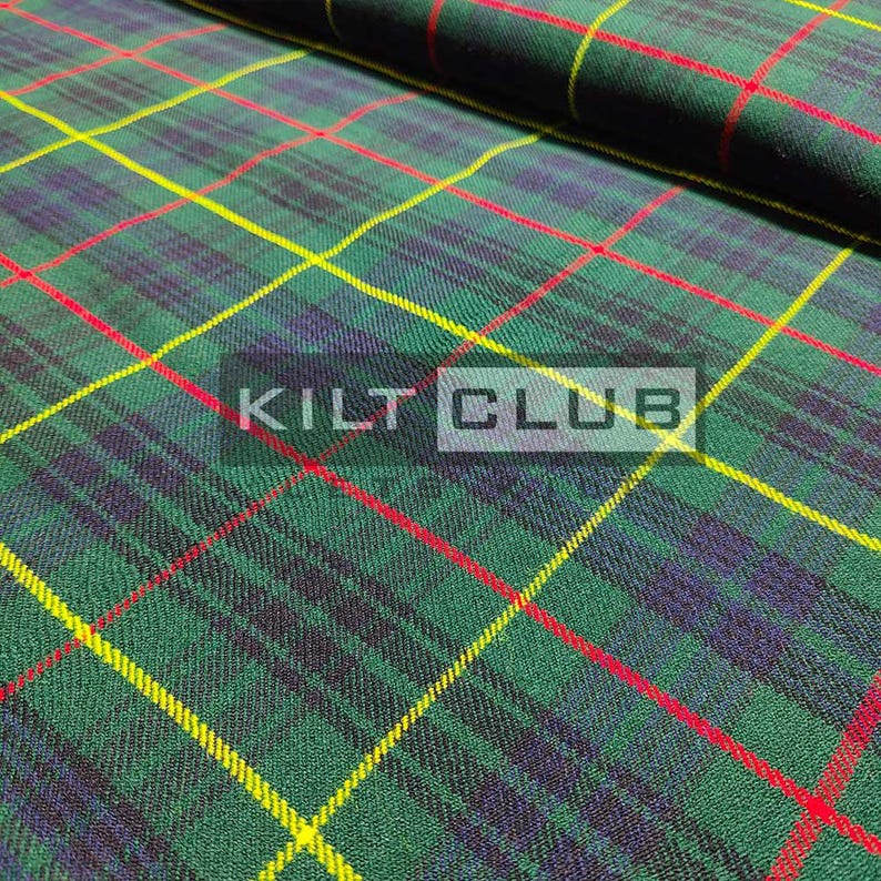 May include: Green, red, yellow, and navy blue plaid fabric. The fabric has a diagonal pattern with intersecting lines. The text "KILT CLUB" is printed on the fabric. The fabric is folded over in the upper right corner.