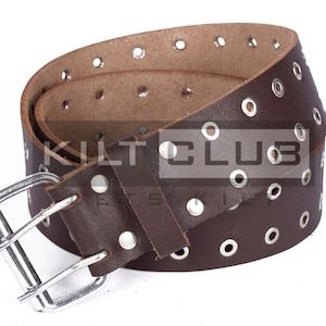 May include: A brown leather belt with multiple eyelets and a silver-colored buckle. The belt has a double-prong buckle and is designed with a series of evenly spaced metal eyelets. The belt is a classic accessory.