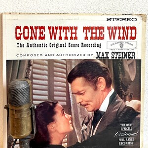 May include: A vintage vinyl record cover for the soundtrack to the movie Gone With The Wind. The cover features a photo of Clark Gable and Vivien Leigh, and the title "Gone With The Wind" in red letters. The text "The Authentic Original Score Recording" and "Composed and Authorized by Max Steiner" is also on the cover.