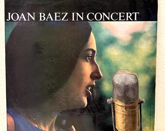 May include: A vintage vinyl record album cover featuring Joan Baez in concert. The cover art shows a close-up of Baez singing into a microphone. The album title "Joan Baez in Concert" is printed in white letters on a black background. The album is a Vanguard recording for the connoisseur.
