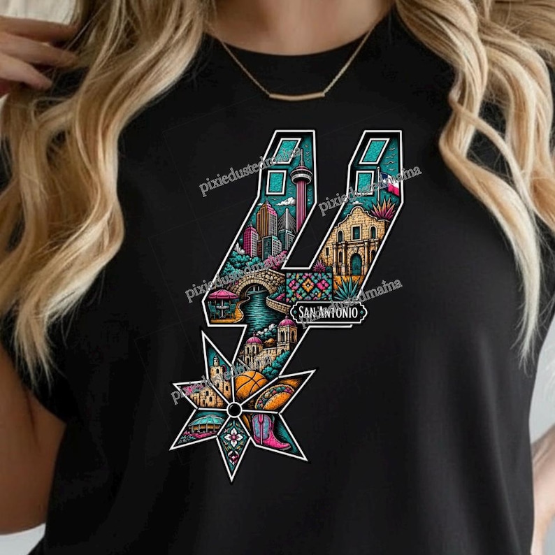 May include: Black t-shirt featuring a colorful graphic of the San Antonio Spurs logo. The logo is filled with illustrations of San Antonio landmarks, including the Tower of the Americas, a bridge, and a mission. The word "SAN ANTONIO" is also included.