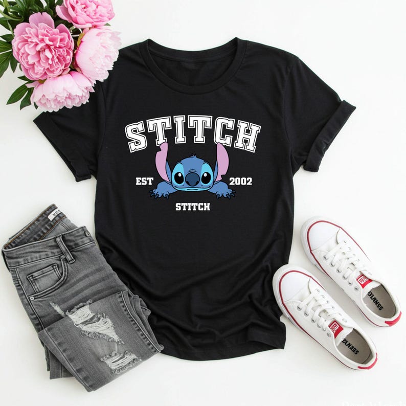 May include: Black t-shirt with a blue Stitch character graphic. The text "STITCH EST 2002" is printed on the shirt.
