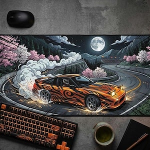 May include: A black computer mouse and a black and orange keyboard sit on a large mousepad. The mousepad features a stylized illustration of an orange sports car drifting on a winding road at night, with a full moon in the sky.