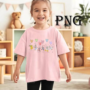 Pode incluir: Uma camiseta rosa claro com um gr&aacute;fico colorido de personagens da Disney segurando bal&otilde;es em forma de Mickey Mouse. Os personagens incluem Pato Donald, Margarida, Mickey Mouse, Minnie Mouse e Pateta. A camisa &eacute; de estilo casual.