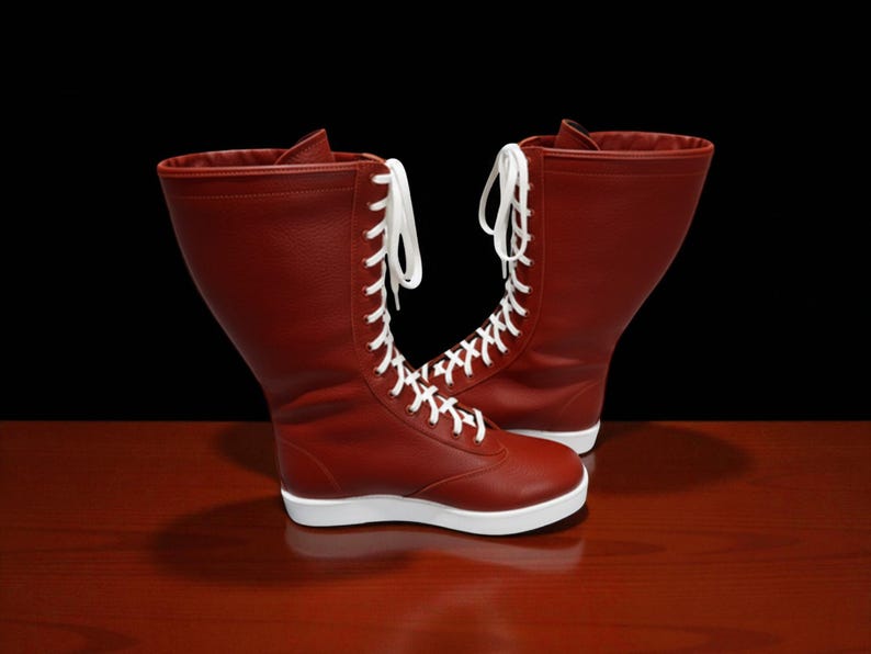 May include: A pair of red leather boots with white laces and soles. The boots have a high-top design and are set against a dark background on a wooden surface.