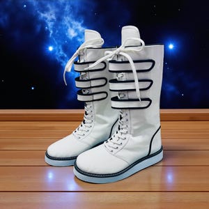 May include: A pair of white boots with black accents. The boots have a lace-up design and three black straps with buckles. The soles are light blue. The boots are on a wooden surface with a starry background.