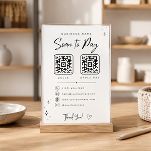 Puede incluir: Un letrero de acrílico transparente en una base de madera con el texto Scan to Pay, Zelle y Apple Pay junto a dos códigos QR. Incluye datos de contacto como teléfono, correo electrónico, sitio web y redes sociales, con Thank You y un corazón.