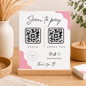 Könnte beinhalten: Ein weißes, rechteckiges Zahlungsschild mit rosa wellenförmigen Akzenten, das den Text Scan to pay, zwei schwarze QR-Codes mit der Beschriftung ZELLE und APPLE PAY, einen Platzhalter für Logos, Social-Media-Symbole, @yourbusinessname und Thank You zeigt.