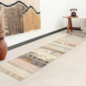 Peut inclure: Un tapis de couloir rectangulaire multicolore avec un motif patchwork. Le tapis présente diverses nuances pastel, dont le rose, le bleu et le beige, avec une esthétique vintage et vieillie. Le tapis mesure environ 244 cm de long.