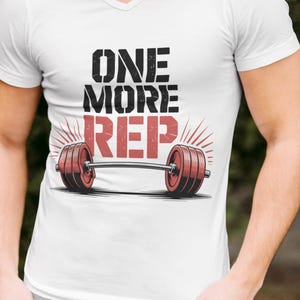 May include: White V-neck t-shirt with the text "ONE MORE REP" above a barbell graphic. The barbell has red weights on each end. The shirt also has the text "Summer Vibes" in the upper right corner.