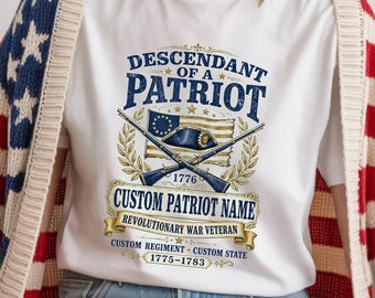 Op de afbeelding: Een wit t-shirt met een afbeelding met de tekst DESCENDANT OF A PATRIOT, CUSTOM PATRIOT NAME, REVOLUTIONARY WAR VETERAN, CUSTOM REGIMENT, CUSTOM STATE en 1775-1783, samen met illustraties van gekruiste musketten, een vlag en een hoed.