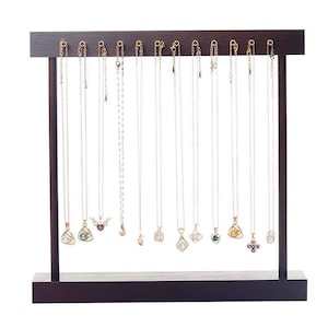 May include: A dark brown wooden jewelry display stand with multiple necklaces hanging from it. The necklaces have various pendant designs, including pearls, gems, and floral shapes. The stand has a rectangular base and a horizontal top bar.