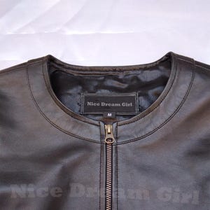 May include: Black leather jacket with a round collar and a full-length zipper. The label inside the collar reads "Nice Dream Girl" and "M". The jacket is a medium size.