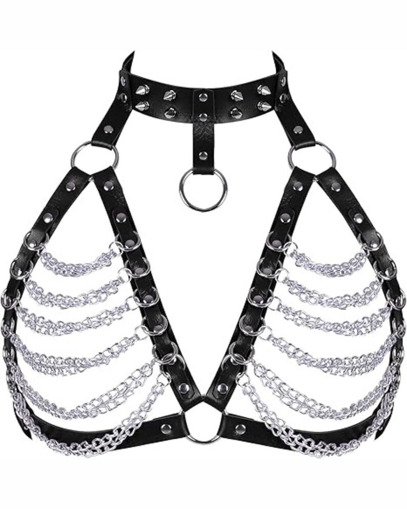 May include: Black faux leather body harness with silver-colored chain and ring accents. The harness features a choker-style neckline with studded details and adjustable straps. The design includes multiple chains that drape across the chest.