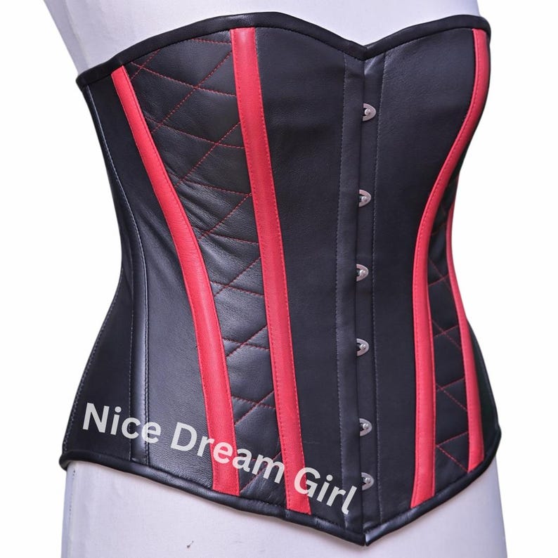 May include: Black corset with red vertical stripes and diamond stitching. The corset has a classic silhouette with a row of silver clasps down the front. The text "Nice Dream Girl" is printed on the bottom left of the corset.