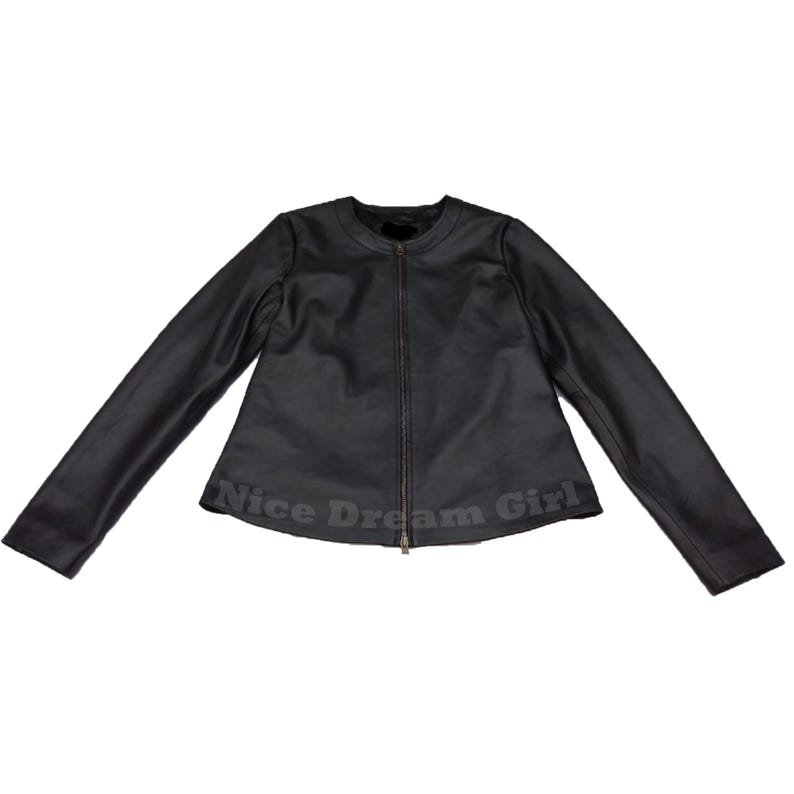 May include: Black leather jacket with a round collar and long sleeves. The jacket has a zipper closure and the words "Nice Dream Girl" are printed at the bottom.