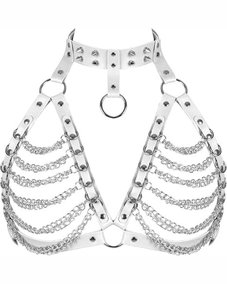 May include: White faux leather body harness with silver-tone metal chain and ring accents. The harness features a choker-style collar with studded details and adjustable straps. The design includes multiple rows of dangling chains.