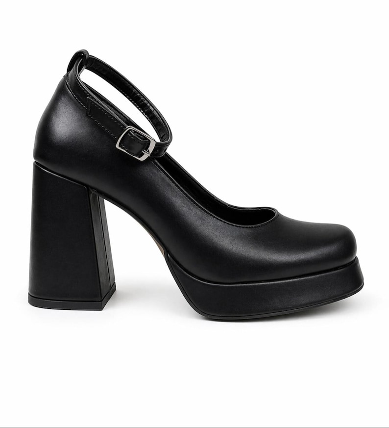 May include: A black platform shoe with a square toe and a high, thick block heel. The shoe features a thin ankle strap with a silver-toned metal buckle closure. The design includes a smooth finish and a substantial platform sole under the forefoot.