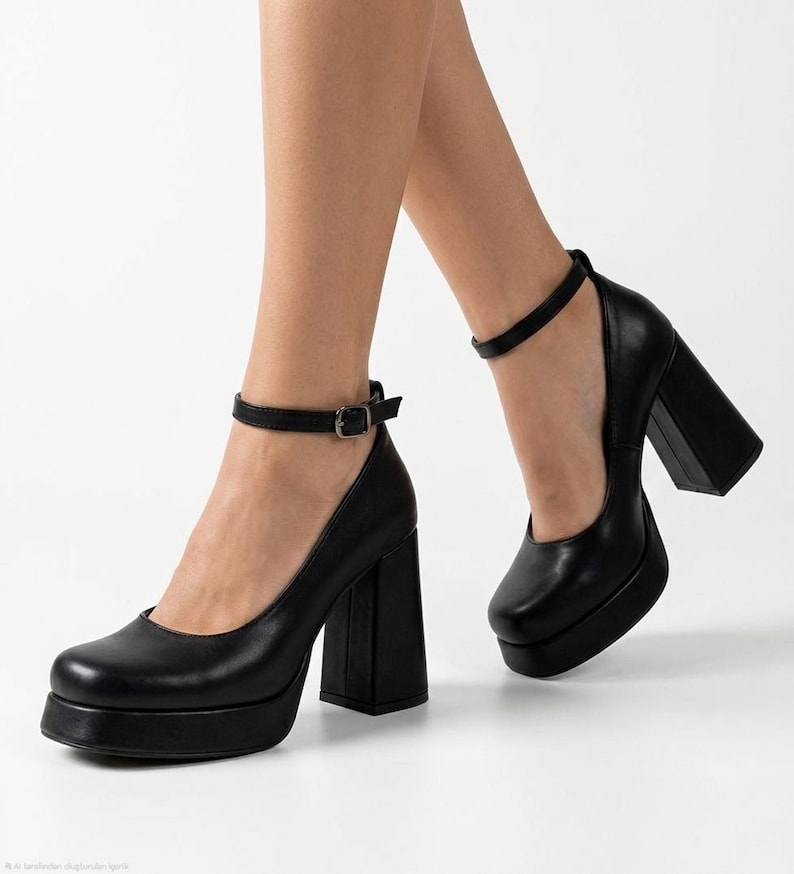 May include: A pair of black platform pumps featuring a square toe, a thick block heel, and a thin ankle strap with a silver-toned metal buckle. The shoes have a smooth finish and a substantial platform sole, providing a solid base and elevation.