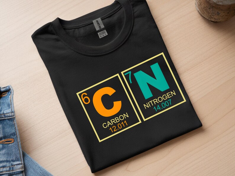 May include: Black t-shirt featuring the periodic table elements Carbon and Nitrogen. The orange 'C' for Carbon is next to the teal 'N' for Nitrogen. The atomic numbers, names, and weights are displayed in yellow boxes.
