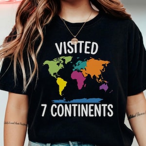 May include: Black t-shirt with the words "VISITED 7 CONTINENTS" in white. The shirt features a colorful world map design, with each continent highlighted in a different color. A travel-themed graphic tee.