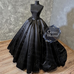 Könnte beinhalten: Ein schwarzes Ballkleid aus Satin, das auf einer Schaufensterpuppe präsentiert wird. Das Kleid hat ein eng anliegendes Oberteil und einen weiten, fließenden Rock. Das Kleid ist einfarbig schwarz und hat eine glänzende Oberfläche. Das Bild enthält den Text "Gothic Whisper".