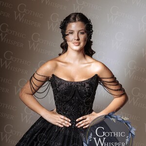 Op de afbeelding: Een zwarte strapless jurk met kralenaccenten en een volle rok. De jurk heeft ingewikkelde borduursels en kralen op de schouders. Een zwarte sluier en het "Gothic Whisper" logo zijn ook zichtbaar.