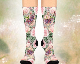 May include: A pair of knee-high socks featuring a floral and butterfly pattern. The socks display pink roses and purple butterflies on a light gray background. The word "LOVE" is printed on the toe of each sock. The heels and toes are black.