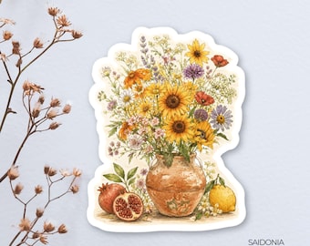 May include: A sticker featuring a watercolor illustration of a bouquet of sunflowers, daisies, and other wildflowers in a rustic vase. Two pomegranates and a lemon are at the base of the vase. The sticker has a white border and the text "SAIDONIA Studios!"