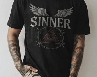 May include: Black t-shirt with a graphic print of a winged eye inside a triangle with barbed wire around it. The text "SINNER" is printed above the graphic. The text "I LOVE I HATE" is printed on the neckline.