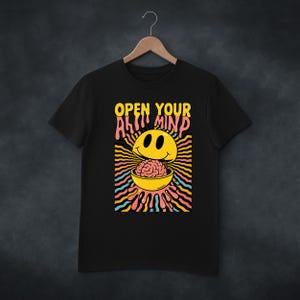 May include: Black t-shirt with a graphic design featuring a yellow smiley face with a brain in a bowl. The text "OPEN YOUR MIND" is above the smiley face in yellow and pink.
