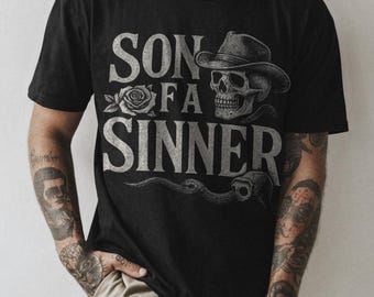 May include: Black t-shirt with a white graphic print of a skull wearing a cowboy hat and the text "SON OF A SINNER".