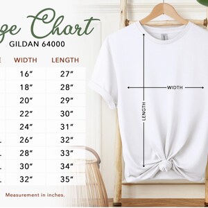 May include: A white Gildan 64000 t-shirt hangs on a wooden hanger. The image includes a size chart with measurements in inches: XS (16" width, 27" length) to 5XL (32" width, 35" length). The chart is labeled "Size Chart".