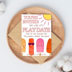Op de afbeelding: Een kleurrijke uitnodigingskaart met de tekst "YOU'RE INVITED!" en "PLAY DATE". De kaart toont cartoon ijsjes en een zon illustratie. De uitnodiging ligt op een houten bord met een bruine envelop.