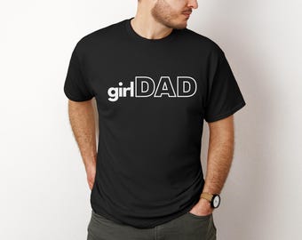 May include: Black t-shirt with the white text "girl DAD". The shirt is a crew neck style and appears to be made of a soft material. The text is in a bold, sans-serif font.