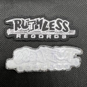 Pode incluir: Patch bordado em preto e branco com o texto "RUTHLESS RECORDS". O patch tem formato retangular com borda branca e está colocado sobre uma superfície preta texturizada. A parte de trás do patch também é visível.
