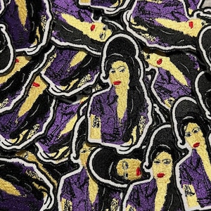 May include: A collection of embroidered patches featuring a stylized portrait of a woman with black hair, red lipstick, and a purple jacket. The patches have a white border and are scattered across the image.