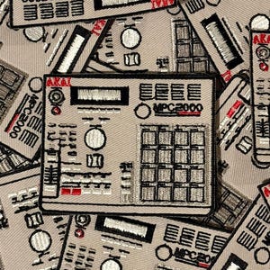 Puede incluir: Un conjunto de parches beige con un diseño bordado detallado de un centro de producción musical Akai MPC2000. Los parches tienen detalles en negro, blanco y rojo, con el texto "MPC2000" visible.