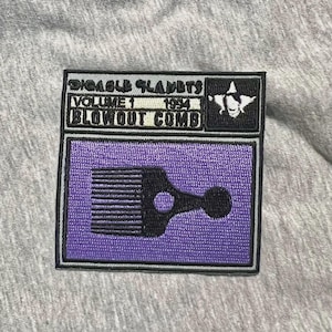 Pode incluir: Um patch retangular com o texto "DIGABLE PLANETS VOLUME 1 1994 BLOWOUT COMB" em branco. O patch apresenta um gráfico de pente preto sobre um fundo roxo, com uma borda preta. Um gráfico em preto e branco está no canto superior direito.