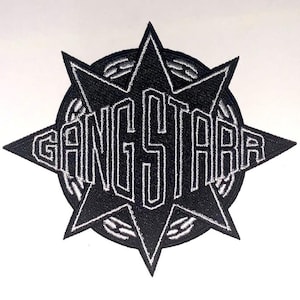 Puede incluir: Parche bordado en blanco y negro con la palabra "GANGSTAR" en una fuente audaz y estilizada. El texto está dentro de un diseño de estrella, con un borde circular. Para ropa o accesorios.
