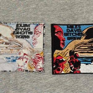 May include: Two embroidered patches featuring artwork and text. One patch has a red and white design with the text "Miles Davis Bitches Brew" in reverse. The other patch has a black background with a red face and the same text.