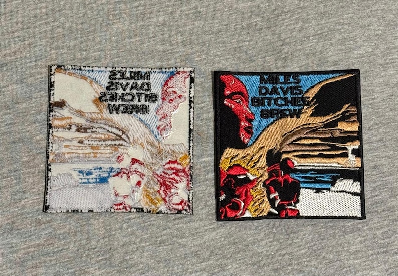 May include: Two embroidered patches featuring artwork and text. One patch has a red and white design with the text "Miles Davis Bitches Brew" in reverse. The other patch has a black background with a red face and the same text.